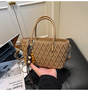 Detail der khakifarbenen gewebten Beuteltasche mit Holzperlenquaste und Schultergurt
