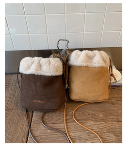 Detail view of suede bucket bags with faux fur trim and embroidered logo in brown colors