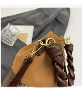 Detail of drawstring bucket bag showing contrast textures and woven leather handle