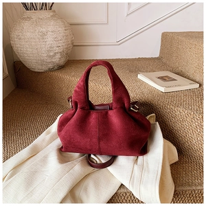 Detailed close-up of burgundy frosted suede bucket bag with elegant golden hardware