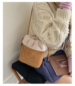 Detail of a brown suede bucket bag with beige faux fur trim and drawstring closure