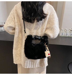 Dettaglio borsa nera in peluche con manico in pelle e ciondolo a forma di toast