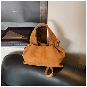 Detail of camel suede bucket bag showing soft pleated texture and gold metal buckle accents