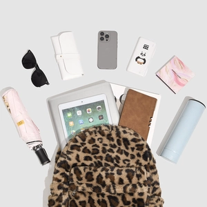 Detailed interior storage view of leopard plush backpack with laptop and daily essentials