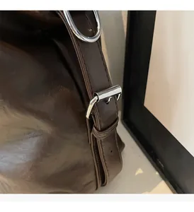 Detailed macro view of dark brown oil-wax leather texture and shiny silver metal hardware