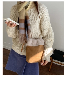 Detail view of brown suede bucket bag featuring plush faux fur trim and gold logo