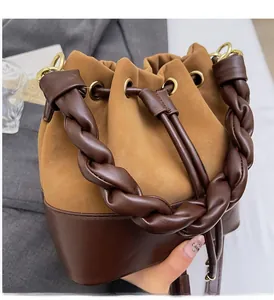 Detail view of woven top handle and drawstring closure on two-tone suede bucket bag