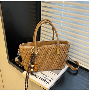 Detail der dunkelbraunen Beuteltasche mit Steppmuster, Metallringen und Holzperlen