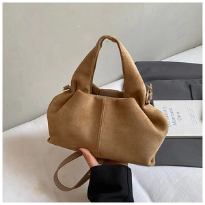 Detailed close-up of a vintage tan suede bucket bag with leather trim and fine straps