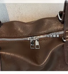 Detail shot of the smooth silver dual zipper on a dark brown leather travel tote bag