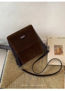 Detail of the brown crossbody bag with matte flap and NO FILTER label on rattan chair