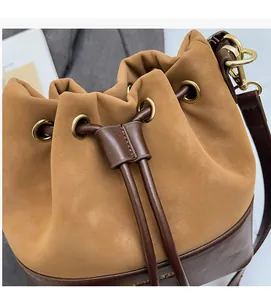Close-up of khaki and brown drawstring bucket bag with gold metal eyelets and soft texture