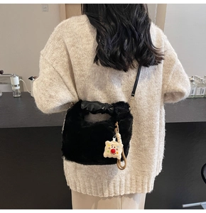 Dettaglio della borsa a secchiello nera in peluche con manico in pelle e ciondolo a forma di orso