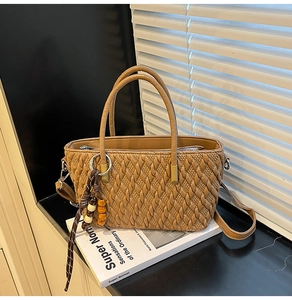 Detail der karamellfarbenen gewebten Handtasche mit Perlenquaste und Trageriemen