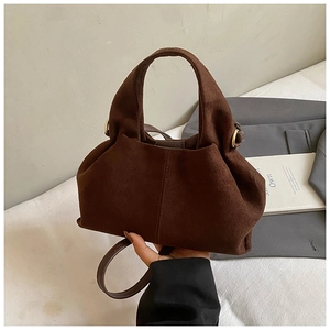 Detail of dark brown matte suede bucket bag with gold ring hardware and shoulder strap