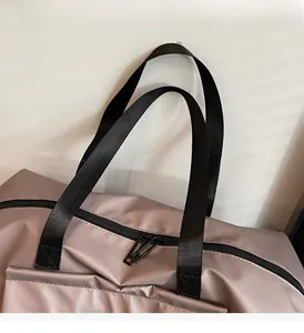 Close-up of champagne purple travel bag featuring durable black handles and zippers