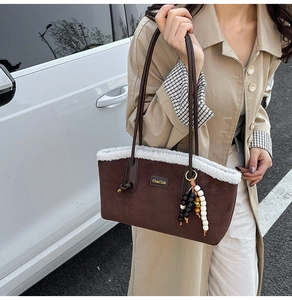 Détail du sac cabas en daim marron avec bordure en fausse fourrure et breloque en bois