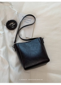 Detail view of retro brown faux leather bucket bag with visible stitching and adjustable strap