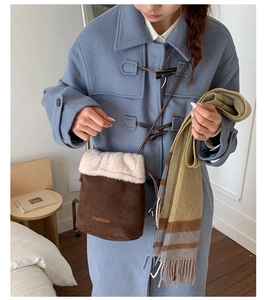 Brown suede bucket bag with white faux shearling trim shown on a model in winter outfit