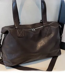 Close-up of soft brown leather travel bag showing refined texture and silver hardware