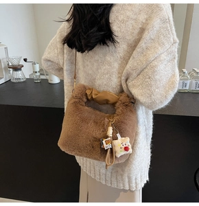 Dettaglio della borsa a secchiello in peluche marrone con manico in pelle e ciondolo