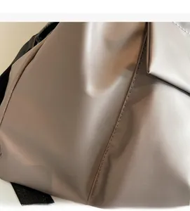 Detail of grey nylon travel bag showing soft fabric texture and quilted side stitching