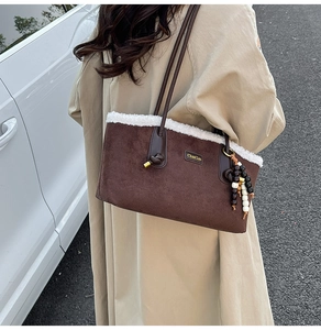 Gros plan sur un sac cabas en daim marron avec bordure en polaire blanche et logo en métal