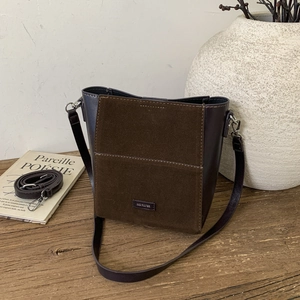 Detail of dark brown bucket bag featuring NO FILTER logo and mixed texture finish