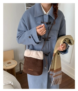 Detail of dark brown suede bucket bag with cream shearling trim and long leather strap