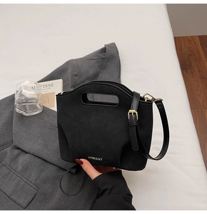 Close-up of black matte bucket bag with unique hollow handle and gold hardware details