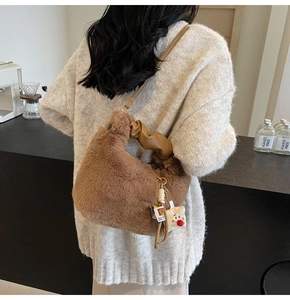 Dettaglio della borsa di peluche marrone con manico in pelle e ciondolo a forma di orso