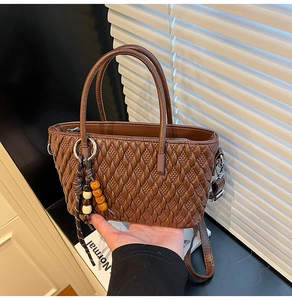 Detail der braunen Web-Eimertasche mit Metallring und bunten Holzperlen-Anhängern