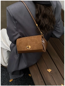 Détail du sac bandoulière en daim marron et cuir verni avec fermoir rotatif doré