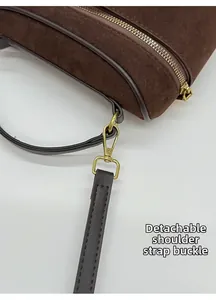 Détail du sac en daim marron foncé avec fermeture éclair en métal et crochet de bandoulière
