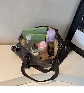 Close-up of spacious interior of dark brown leather tote bag with various daily essentials