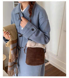 Close-up of brown suede bucket bag featuring faux shearling trim and logo branding