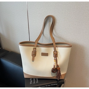 Detail of lychee pattern PU leather tote bag with tassel charm and logo plaque