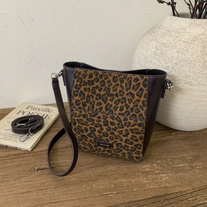 Detail of leopard print bucket bag with NO FILTER leather tag on rustic wood