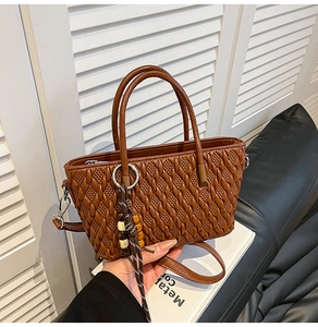 Detail der dunkelbraunen Webstruktur-Handtasche mit Metallringgriff und Perlen-Quaste