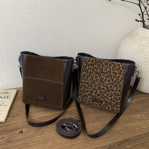 Detail view of suede and leopard print bucket bags with leather trim and metal logo