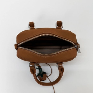 Top view of brown Boston bag showing zip opening, striped lining and strawberry charm