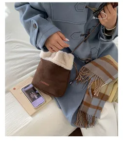 Detailed top view of brown suede bucket bag with white fur trim on white linen
