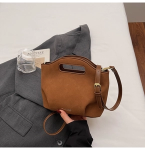 Detailed shot of caramel suede bucket bag with integrated oval handle and leather strap