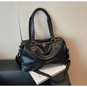 Detail of black leather tote bag with dual zippers and adjustable fabric shoulder strap