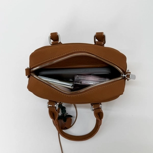 Top view of spacious brown leather handbag interior with daily essentials and silver zipper