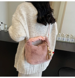 Dettaglio della borsa a spalla rosa in peluche con manico in pelle e ciondolo bambola