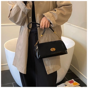 Détail d'un sac à bandoulière en cuir verni noir vintage avec fermoir rotatif doré