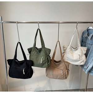Corduroy tote bags in four colors hanging on a rack showing textures and zipper pockets