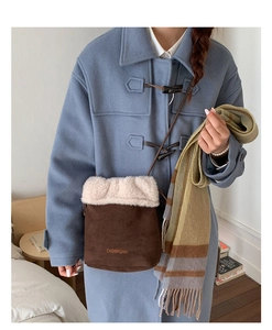 Close-up of brown suede bucket bag featuring white faux fur trim and embroidered logo detail