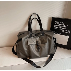 Detail of grey travel bag with buckle front pocket, sturdy handles and adjustable strap